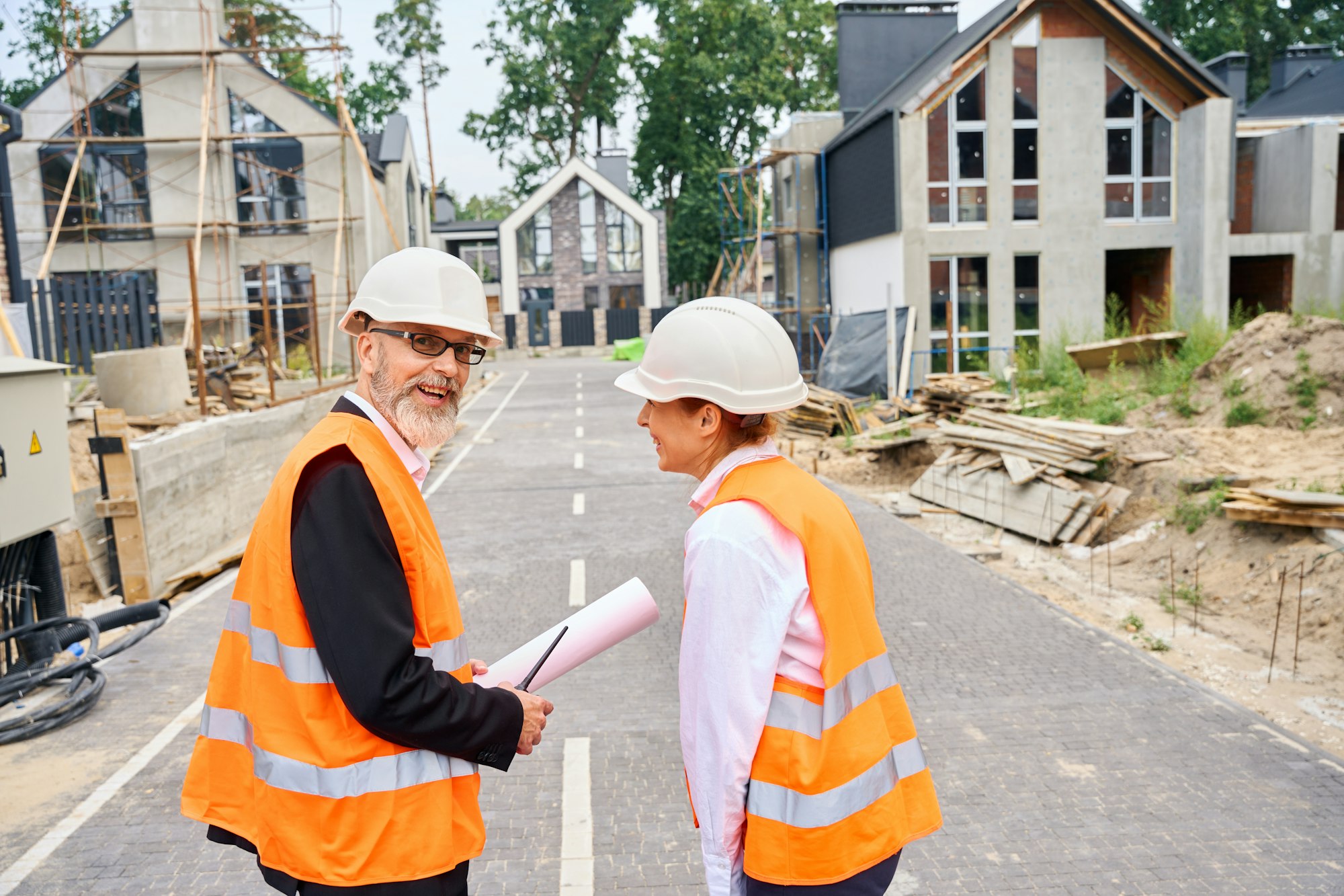 Cheerful construction staff in front of half-built residential houses